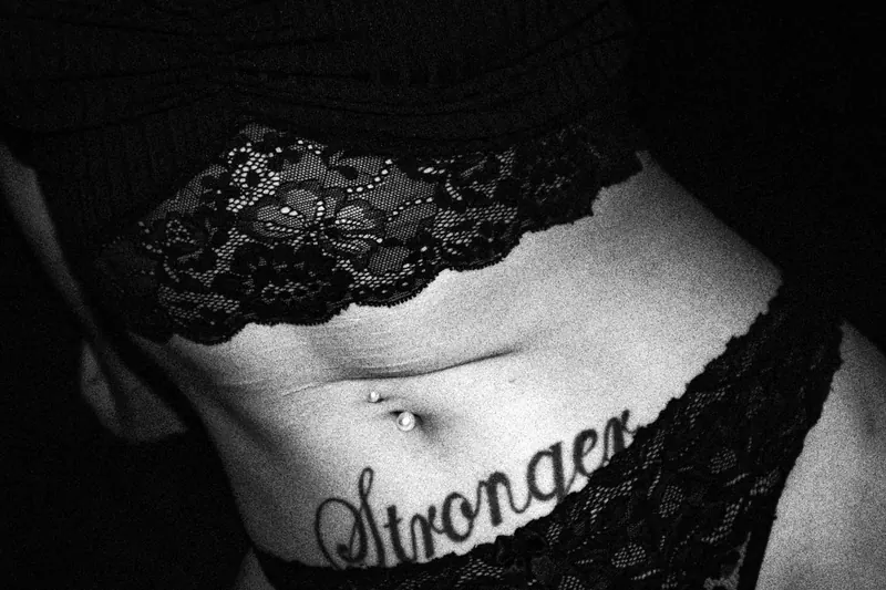 Close view of lace clothing and a lettering tattoo across Gotho’s abdomen