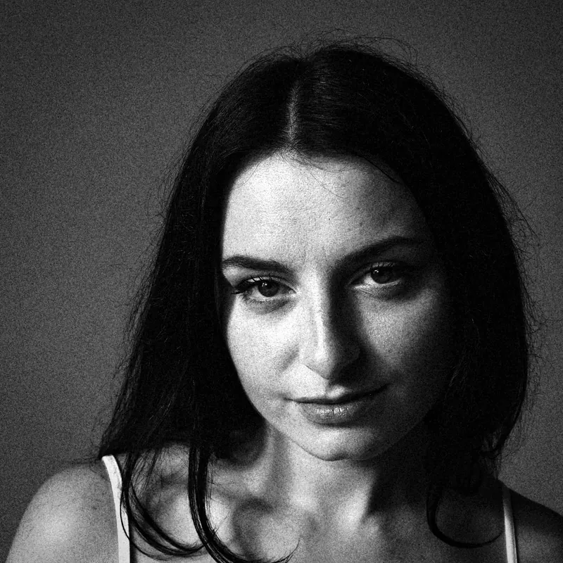 Close portrait of Magdalene facing the camera against a dark backdrop