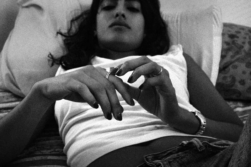 Vanessa reclining against pillows with hands resting over a light tank top