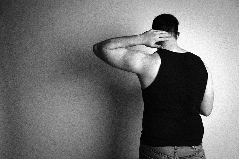 James seen from behind in a tank top, with a hand at the back of the neck