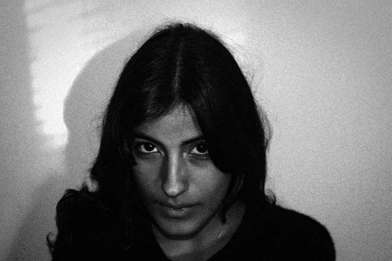 Close portrait of Vanessa against a light wall with a strong shadow