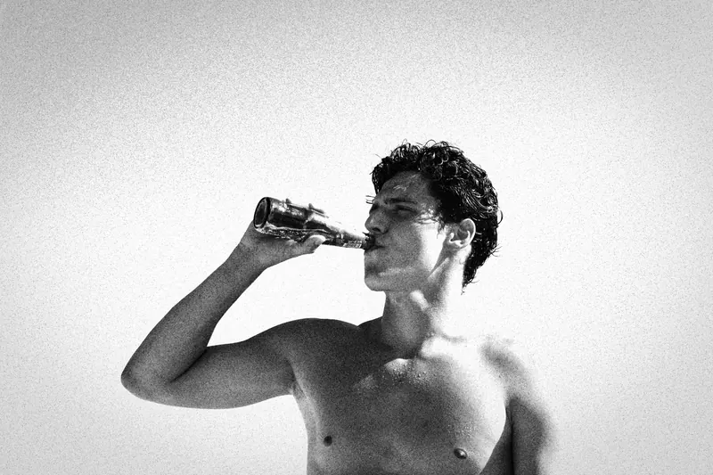 Charlie drinking from a bottle in profile by the sea