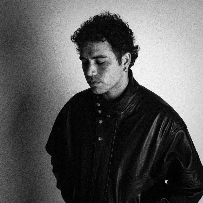 Marco looking down in a buttoned leather jacket