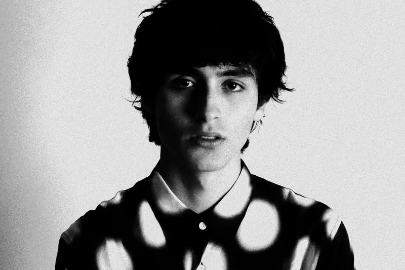 Marcel facing the camera in a collared shirt with large light spots