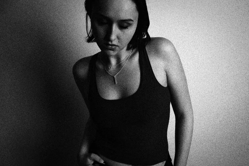 Alyssa standing in a dark tank top with eyes lowered