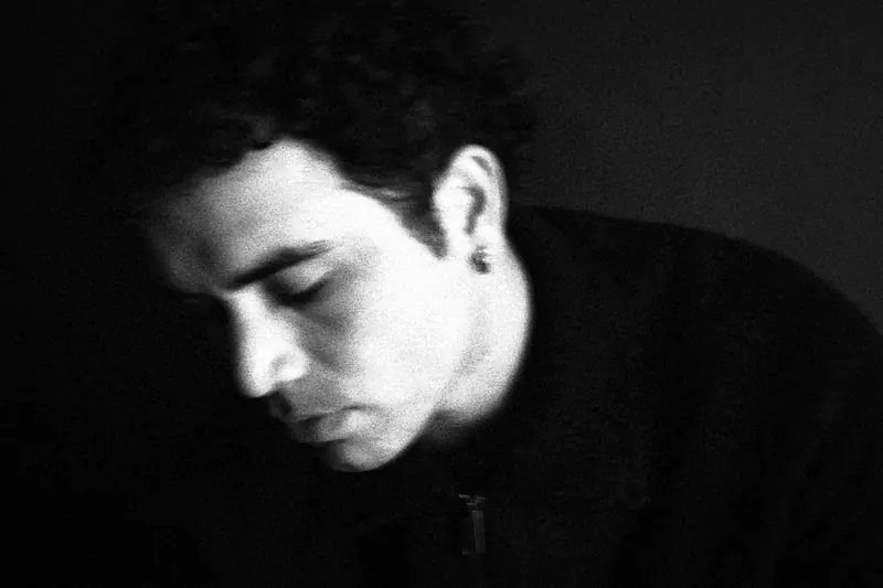 Marco leaning forward with eyes lowered in a close portrait