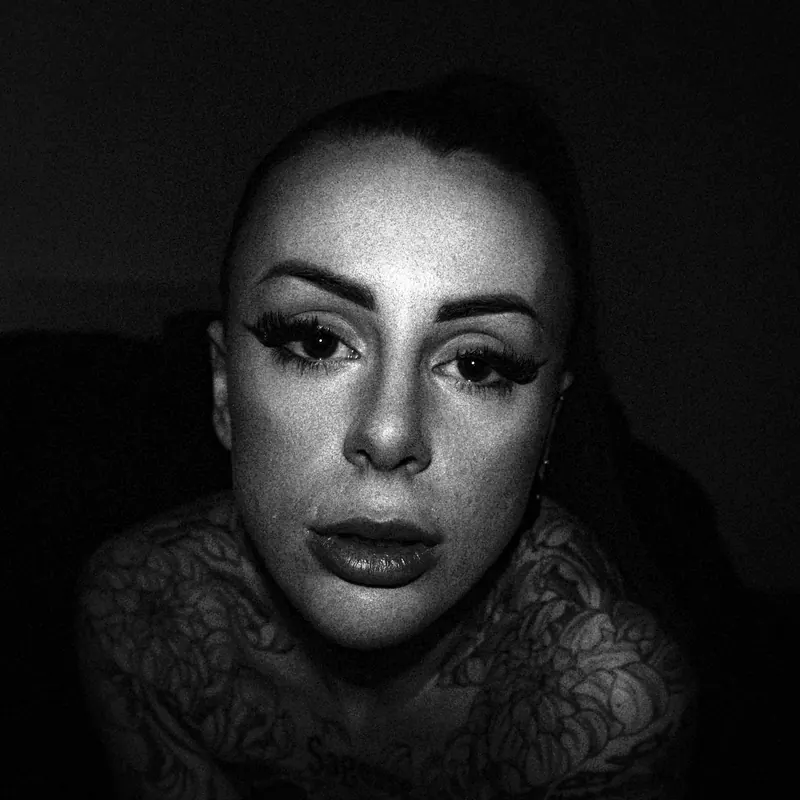 Close portrait of Gotho facing the camera, with tattoos visible at the shoulders