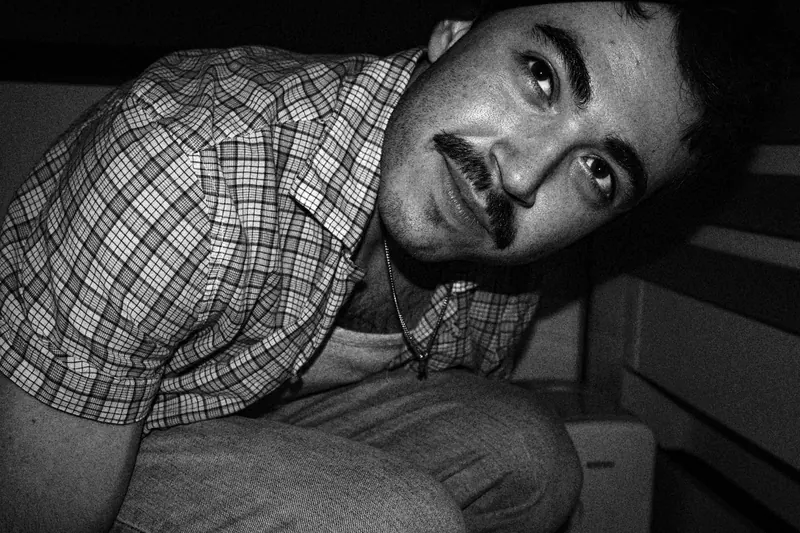 Tristan leaning toward the camera in a checked shirt