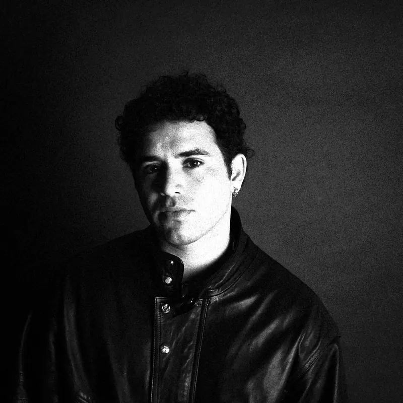 Marco facing the camera in a leather jacket, with one side of the face brightly lit