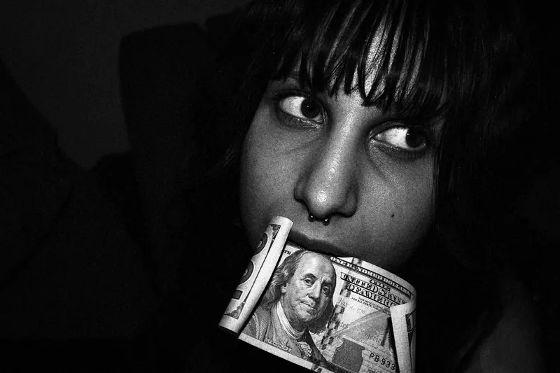 woman with 100 dollar bill in her mouth